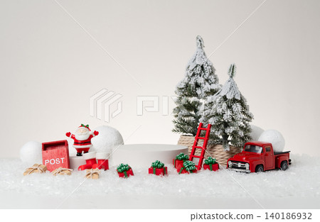 Festive Christmas product display photography featuring a white cylindrical podium, red vintage toy truck, Santa Claus figurine, red mailbox, wooden ladder, ornament ball and wrapped gift boxes on ar Festive Christmas product display photography featuring a white cylindrical podium, red vintage toy truck, Santa Claus figurine, red mailbox, wooden ladder, ornament ball and wrapped gift boxes on ar 140186932