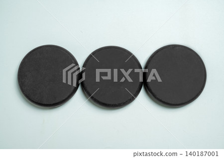 Three small, circular, black industrial ferrite magnets arranged in a horizontal row on a flat, light-colored surface, ideal for physics, science, or DIY concepts Three small, circular, black industrial ferrite magnets arranged in a horizontal row on a flat, light-colored surface, ideal for physics, science, or DIY concepts 140187001