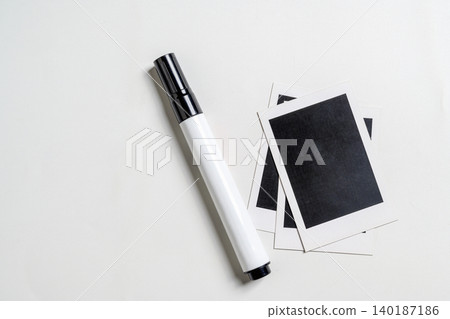 Top-down view of a white marker and several blank instant film photos with black centers arranged on a light gray textured surface, creating a minimalist creative workspace Top-down view of a white marker and several blank instant film photos with black centers arranged on a light gray textured surface, creating a minimalist creative workspace 140187186