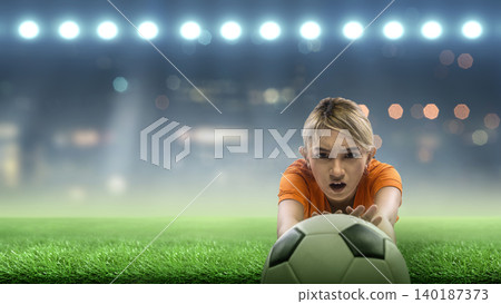 A Indonesian southeast asian female soccer or football goalkeeper in an orange jersey dives to catch the ball on a green field under bright stadium floodlights A Indonesian southeast asian female soccer or football goalkeeper in an orange jersey dives to catch the ball on a green field under bright stadium floodlights 140187373