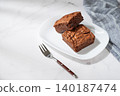 A pieces of chocolate brownie on a white plate on a marble background 140187474