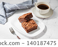 A pieces of chocolate brownie on a plate and a cup of espresso coffee on a marble background 140187475
