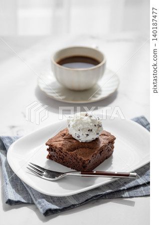 A piece of chocolate brownie with ice cream on a plate and a cup of espresso coffee A piece of chocolate brownie with ice cream on a plate and a cup of espresso coffee 140187477