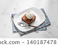 A piece of chocolate brownie with ice cream on a plate on a light marble background 140187478