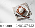 A piece of chocolate brownie with ice cream on a plate on a light marble background 140187482