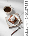 A piece of chocolate brownie with ice cream on a plate and a cup of espresso coffee 140187483