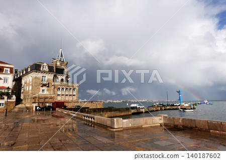 Beautiful historic stone mansion by the sea with a rainbow over the ocean after rain under a cloudy sky Beautiful historic stone mansion by the sea with a rainbow over the ocean after rain under a cloudy sky 140187602