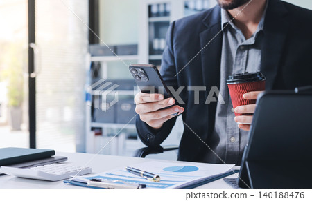 Tired worker. A tired businessman works in the evening. A man in office clothes is holding his temples. Problems in business. The businessman is trying to solve the problems that have arisen. 140188476