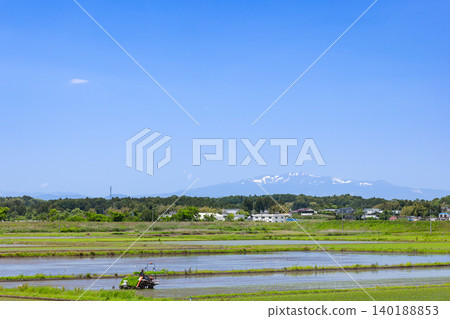 Rice planting with a rice transplanter and the snow-capped Mount Kurikoma. Rice planting with a rice transplanter and the snow-capped Mount Kurikoma. 140188853