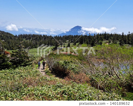 A walking trail in Hachimantai offering a view of Mount Iwate shrouded in clouds. 140189632