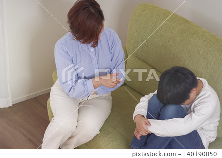 一位母親責罵她的孩子,一個男孩畏縮著退縮 一位母親責罵她的孩子,一個男孩畏縮著退縮 140190050
