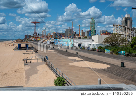 New york, usa august 21,2024. Coney island boardwalk stretching along the beach with the wonder wheel and other amusement park rides under a cloudy sky New york, usa august 21,2024. Coney island boardwalk stretching along the beach with the wonder wheel and other amusement park rides under a cloudy sky 140190296