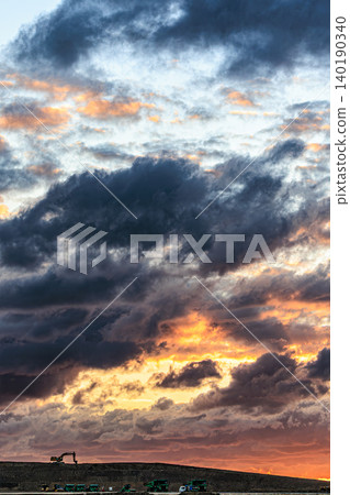 A dramatic twilight landscape painted with sunset clouds and heavy machinery. A dramatic twilight landscape painted with sunset clouds and heavy machinery. 140190340