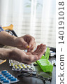 Middle aged caucasian man counts out pills for distributing scheduled dose of medication into pillbox 140191018
