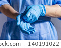 Healthcare professional putting on blue medical gloves on white background with copy space 140191022