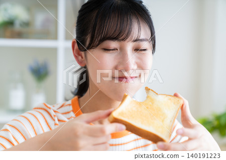 Young woman eating toast 140191223