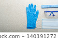 Medical face mask, glasses, hat and gloves laying on table flat lay view with copy-space 140191272