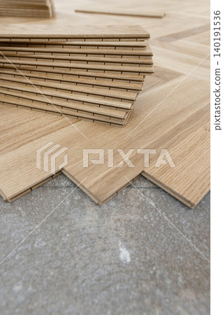 Beige parquet planks on floor during herringbone hardwood flooring installation. Apartment renovation 140191536