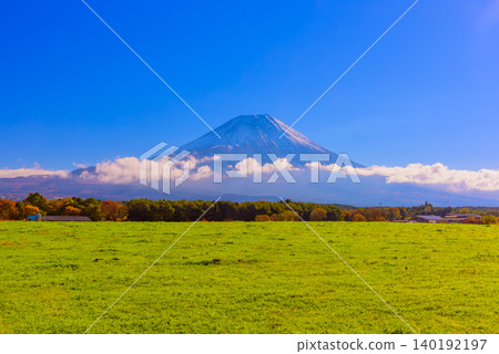 On a clear autumn morning, a panoramic view of snow-capped Mount Fuji, with its wispy clouds and uninhabited peaks, can be seen from a lush green pasture. On a clear autumn morning, a panoramic view of snow-capped Mount Fuji, with its wispy clouds and uninhabited peaks, can be seen from a lush green pasture. 140192197