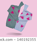 Two cozy knitted turtleneck sweaters with pink heart patterns in grey and light blue colors flying on pastel pink background, copy space. 140192355