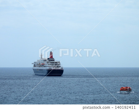 一艘遊輪停泊在八丈島八重根漁港附近的海岸邊。 140192411