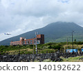 A passenger plane landing with Mount Hachijo-Fuji in the background. 140192622