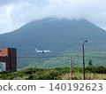 A passenger plane landing with Mount Hachijo-Fuji in the background. 140192623