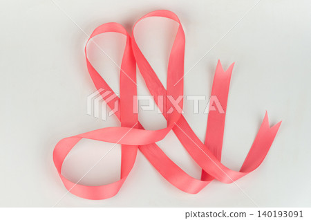 Bright pink ribbon lies on a plain background in a graceful shape Bright pink ribbon lies on a plain background in a graceful shape 140193091