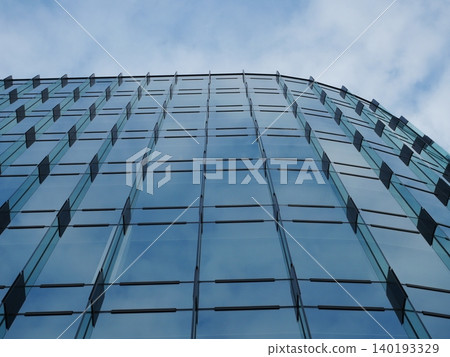 The cityscape of blue sky and clouds reflected in the glass windows of a building. The cityscape of blue sky and clouds reflected in the glass windows of a building. 140193329