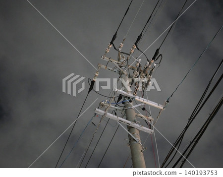 A quiet urban landscape of utility poles and power lines stretching into the night sky. A quiet urban landscape of utility poles and power lines stretching into the night sky. 140193753