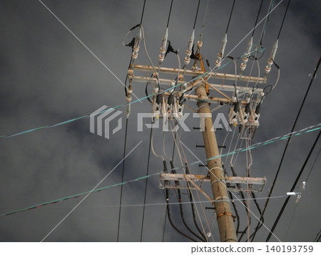 A quiet urban landscape of utility poles and power lines stretching into the night sky. 140193759
