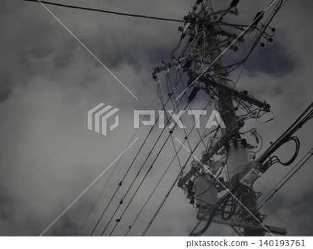A quiet urban landscape of utility poles and power lines stretching into the night sky. 140193761