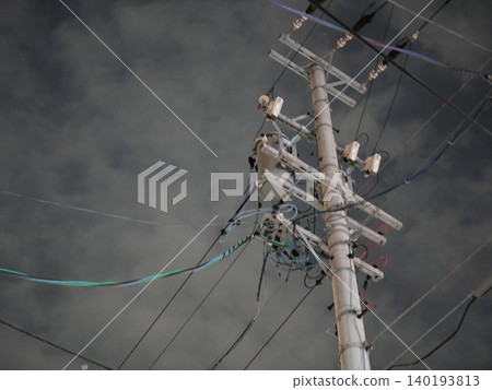 The silent silhouettes of utility poles and power lines stretching into the night sky. The silent silhouettes of utility poles and power lines stretching into the night sky. 140193813