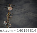 The silent silhouettes of utility poles and power lines stretching into the night sky. 140193814