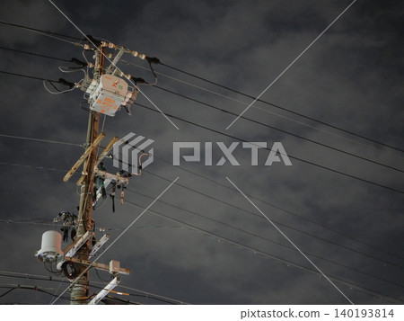 The silent silhouettes of utility poles and power lines stretching into the night sky. The silent silhouettes of utility poles and power lines stretching into the night sky. 140193814