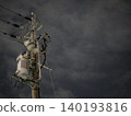 The silent silhouettes of utility poles and power lines stretching into the night sky. 140193816