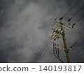 The silent silhouettes of utility poles and power lines stretching into the night sky. 140193817