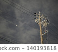 The silent silhouettes of utility poles and power lines stretching into the night sky. 140193818