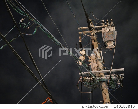 The silent silhouettes of utility poles and power lines stretching into the night sky. The silent silhouettes of utility poles and power lines stretching into the night sky. 140193819