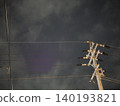 The silent silhouettes of utility poles and power lines stretching into the night sky. 140193821