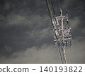 The silent silhouettes of utility poles and power lines stretching into the night sky. 140193822