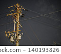 The silent silhouettes of utility poles and power lines stretching into the night sky. 140193826