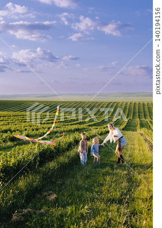 Family flying kite in green field during summer fun Family flying kite in green field during summer fun 140194156