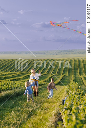 Happy children running with mother flying kite 140194157