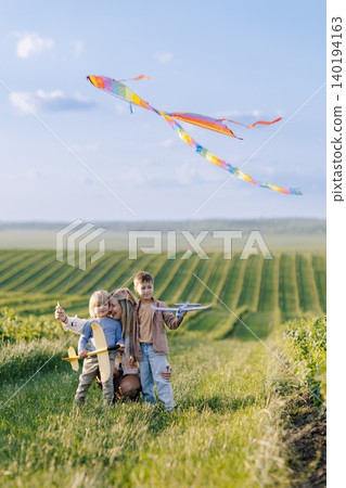 Mother and sons flying kite enjoying summer outdoors Mother and sons flying kite enjoying summer outdoors 140194163