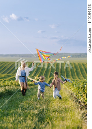 Mother and children flying kite and playing outdoors Mother and children flying kite and playing outdoors 140194168
