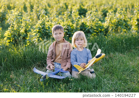 Children playing with toy airplanes in green field 140194227