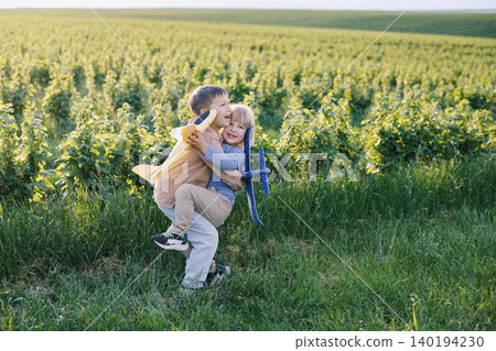 Happy children hugging playing with toy airplanes in field Happy children hugging playing with toy airplanes in field 140194230