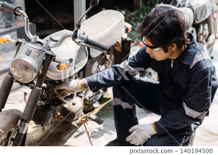 Garage mechanic male worker checkup, fix, replace, service old motorcycle motor bike in workshop. Garage mechanic male worker checkup, fix, replace, service old motorcycle motor bike in workshop. 140194500