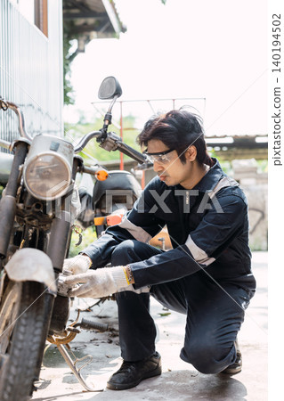 Garage mechanic male worker checkup, fix, replace, service old motorcycle motor bike in workshop. Garage mechanic male worker checkup, fix, replace, service old motorcycle motor bike in workshop. 140194502